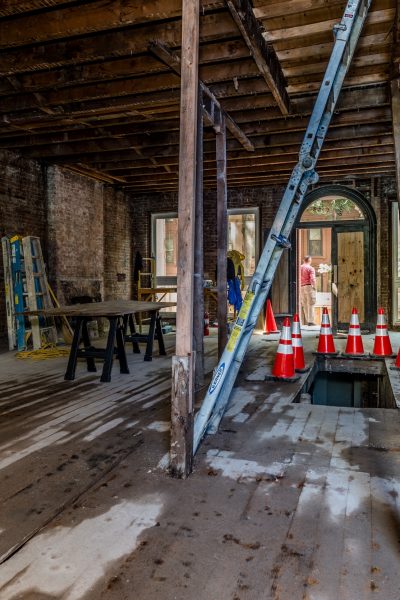 Gutted building interior with exposed brick, wood beams, and safety cones