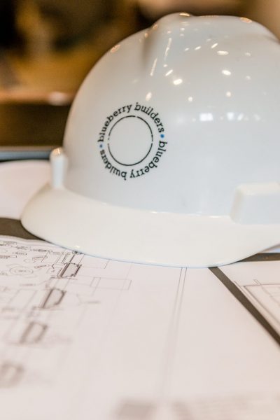Blueberry Builders hard hat resting on architectural blueprints